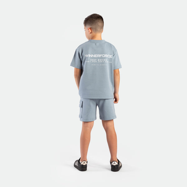 a back view for young boy wearing matching set dusty blue ,t-shirt  with logo and short with pocket ,plus the shoes
