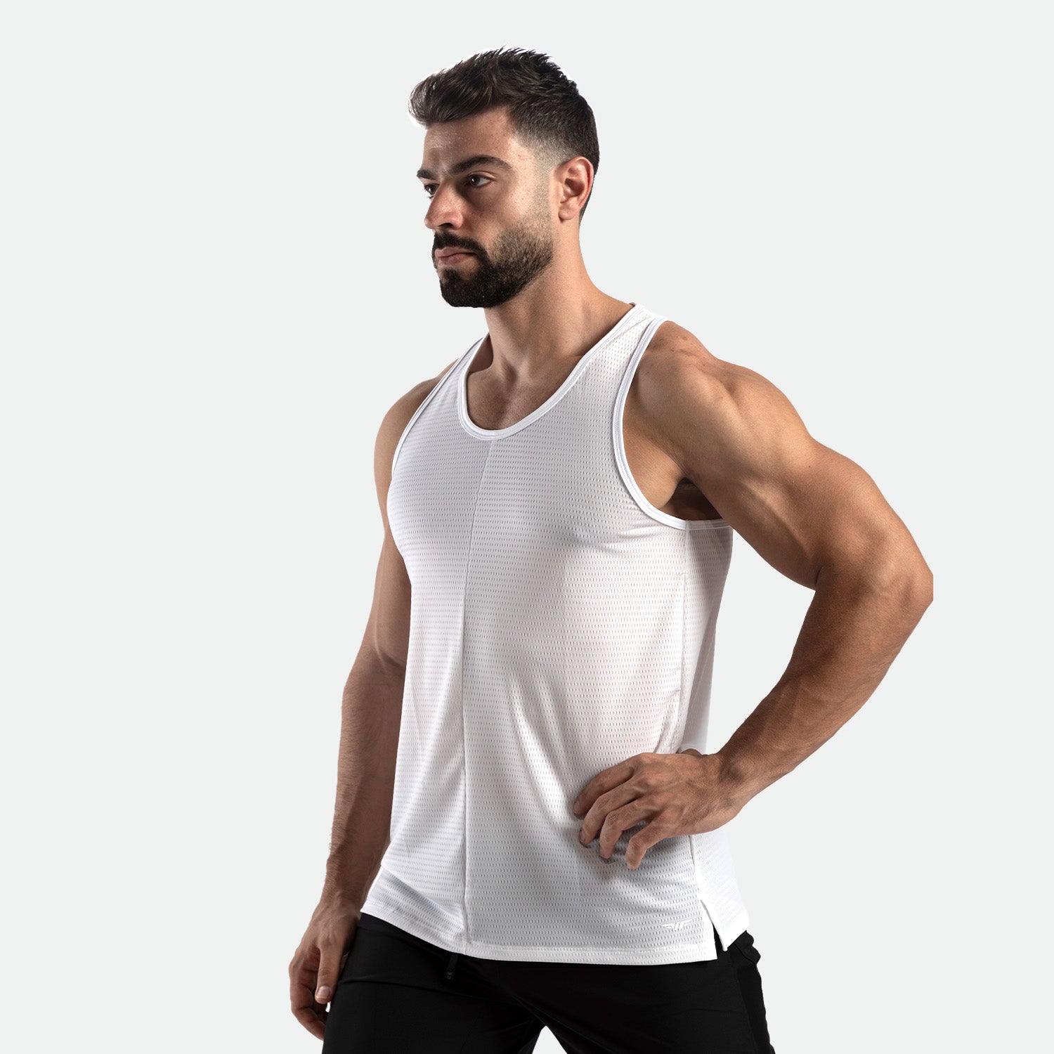 a fit man stand at right and wearing tank white with pants black 