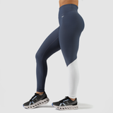  a fit woman stand at the right  and wearing legging mix tow color blue and white ,shoes is same color , plus background is light grey 