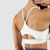 Close-up of a woman's back wearing a stylish white sports bra with cutout detail and crisscross straps