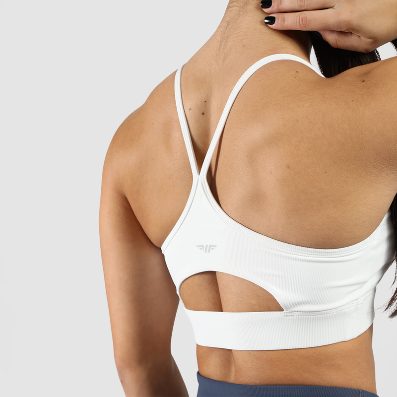 Close-up of a woman's back wearing a stylish white sports bra with cutout detail and crisscross straps