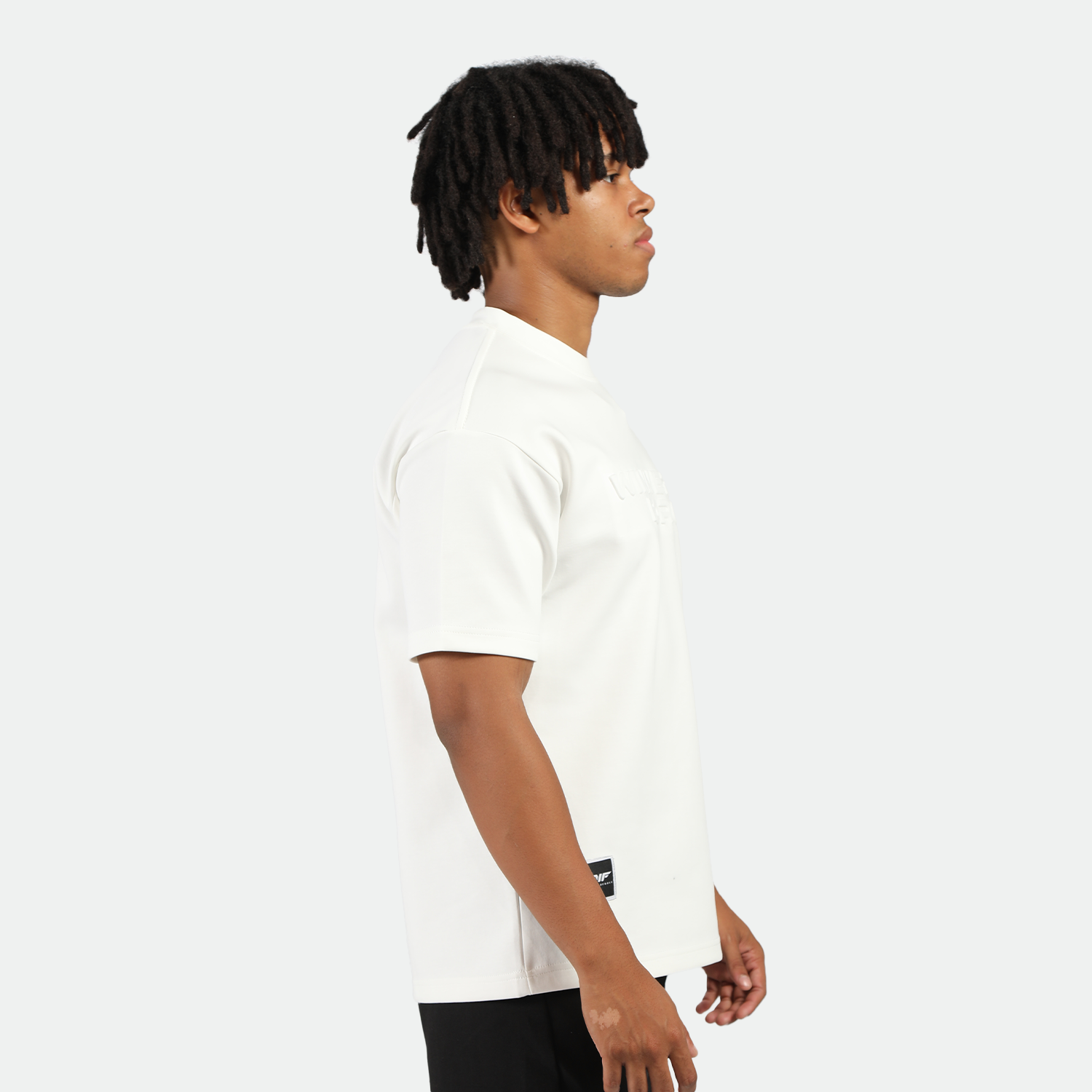a fit man stand at right and wearing t-shirt white with short black 