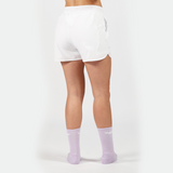 a back view for fit woman wearing short white 2 in 1 with socks purpel ,plus the background is light grey 