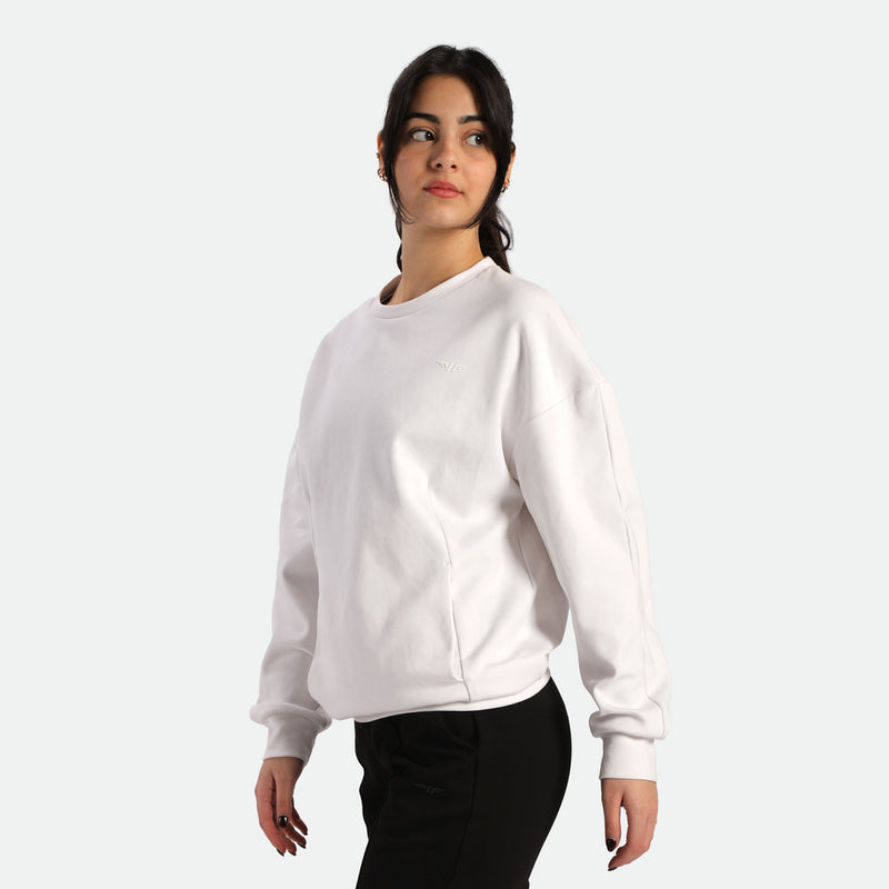A person wearing a casual oversized white sweatshirt and black pants, standing against a plain background.