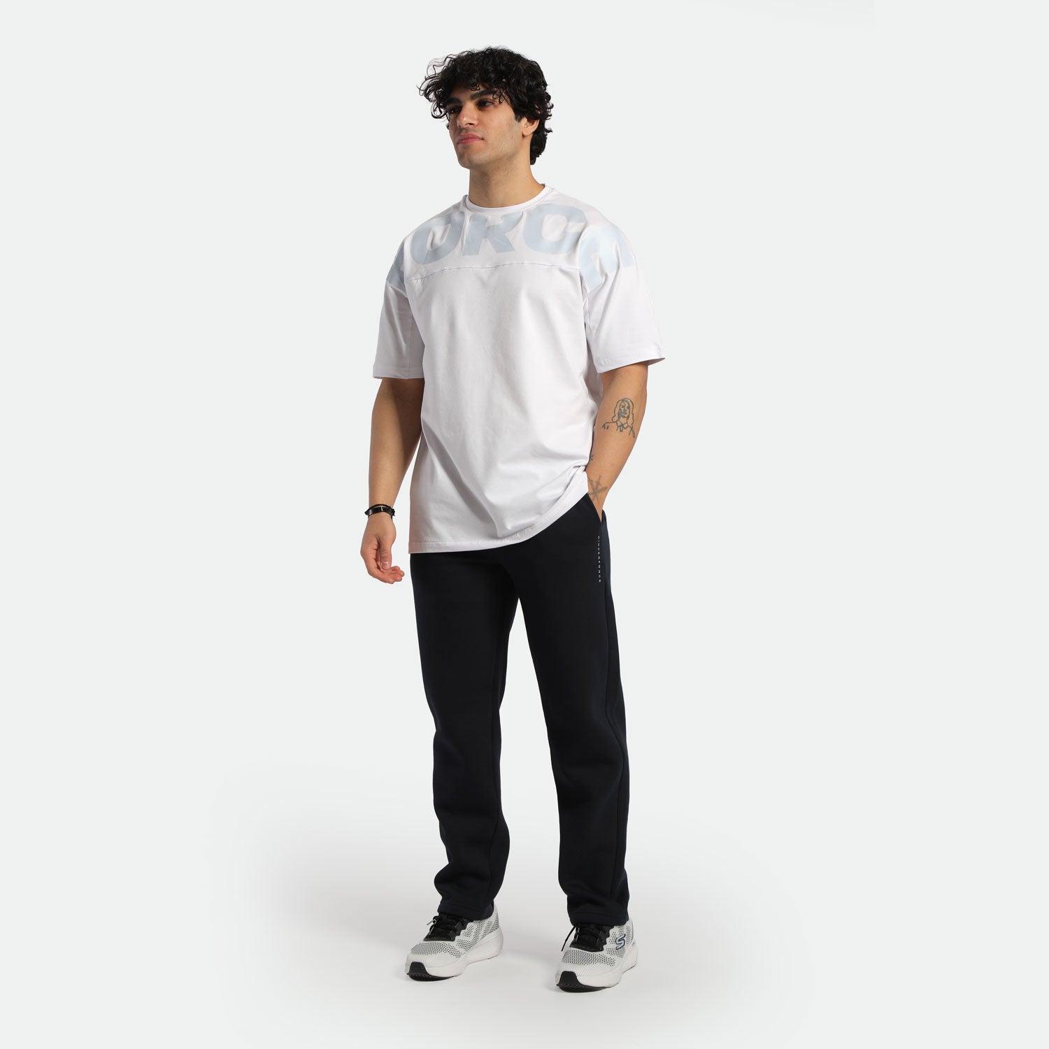 a fit man wearing t-shirt white with pants black ,plus shoes 