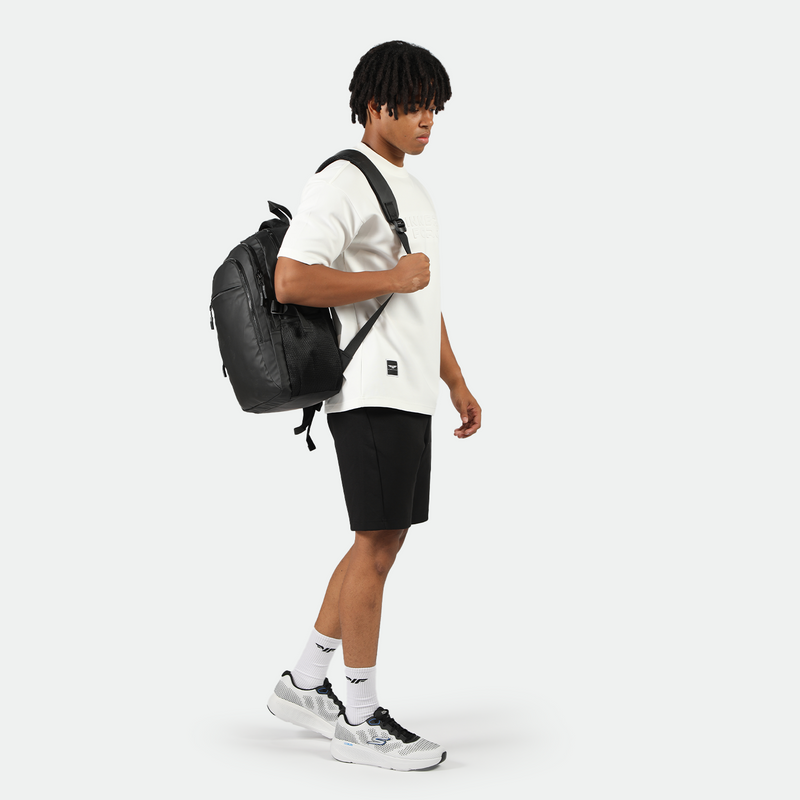 a fit man stand at right  and wearing t-shirt  white with short black ,plus he wearing bag black 