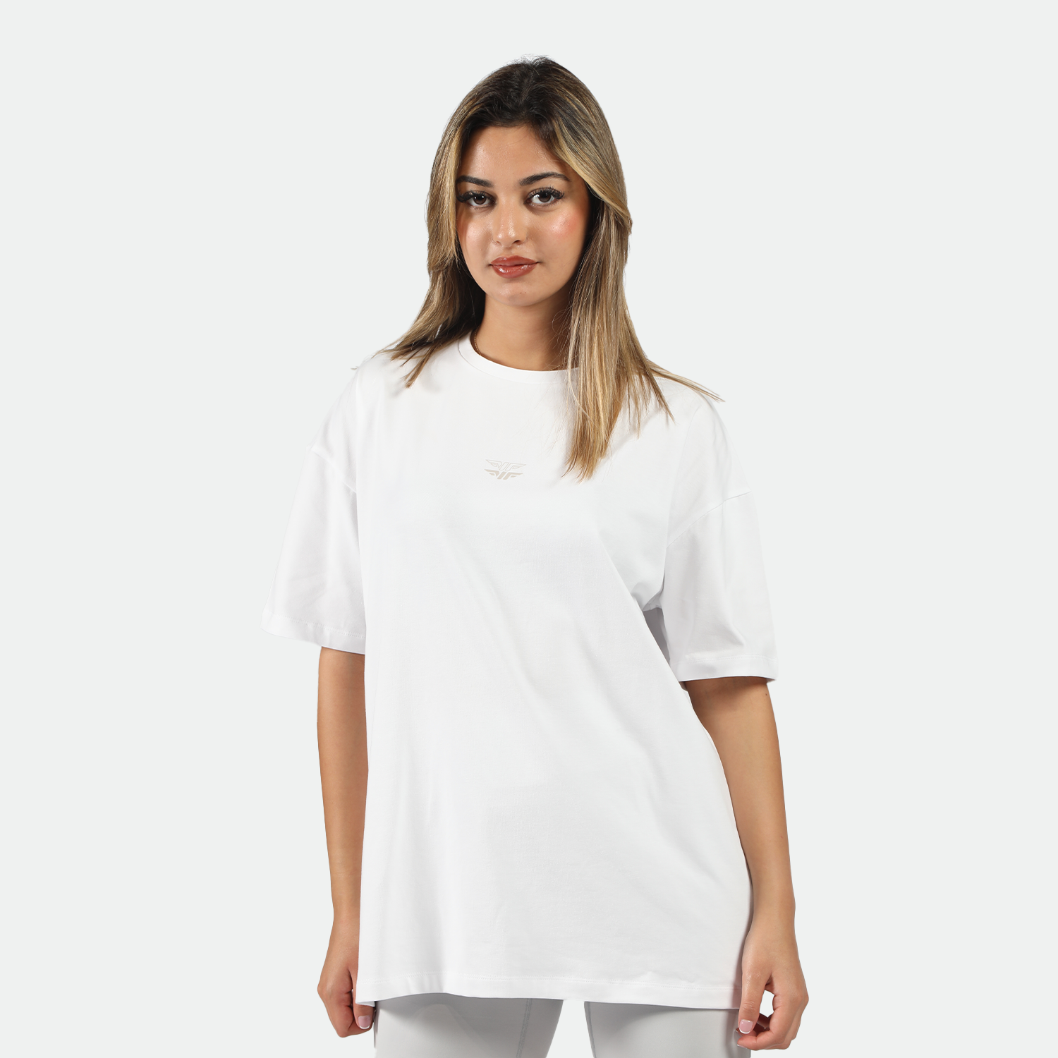 a fit woman look at the camera and wearing t-shirt white with logo and short grey 