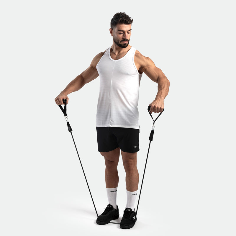 Man wearing a white athletic tank top and black workout shorts using resistance bands during a fitness exercise