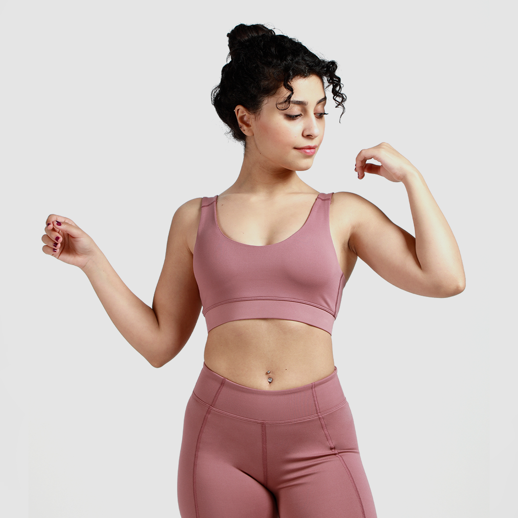Woman wearing matching bra and leggings, quarter pose looking to right, light grey background