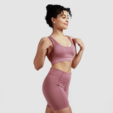 Woman standing in quarter pose looking to right, wearing matching bra and pants, with light grey background