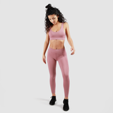 a fit woman wearing matching bra and legging pink ,she wearing shoes black ,plus the background is light grey 