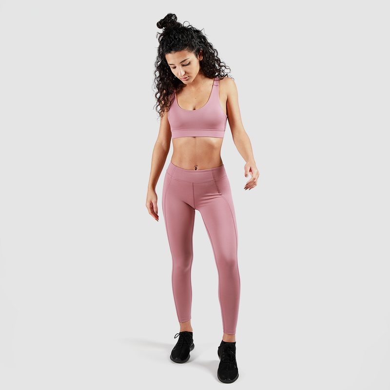 a fit woman wearing matching bra and legging pink ,she wearing shoes black ,plus the background is light grey 