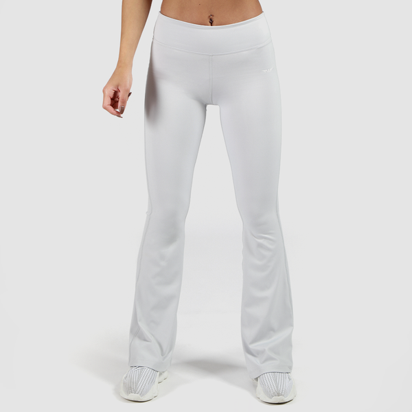 a fit woman wearing flared legging grey with shoes white ,the background is light grey 