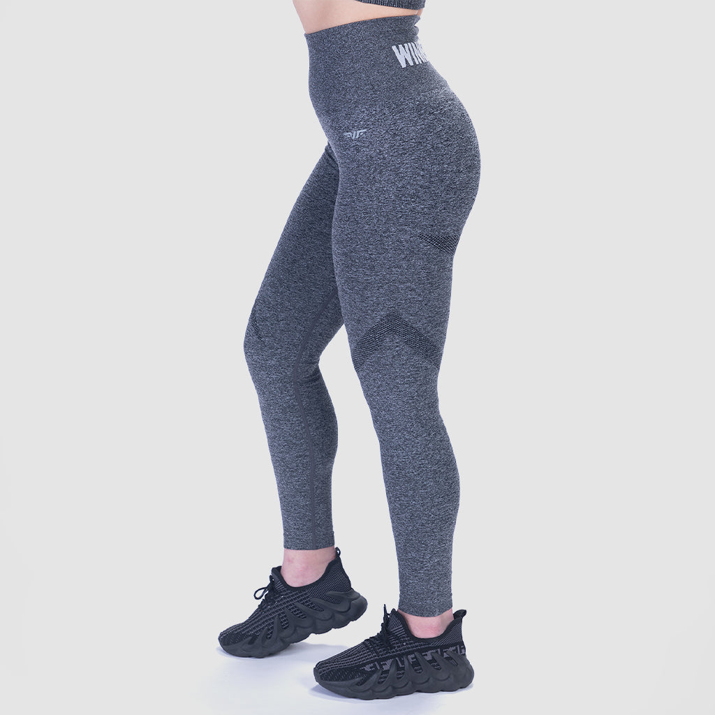 a woman stand at right  and wearing legging grey and shoes black ,plus the background is light grey 