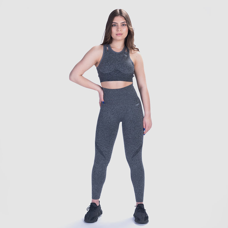 a fit woman wearing matching bra and legging grey with logo ,the background is light grey 
