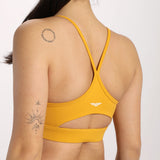 Back view of a woman in a yellow sports bra , standing with her hair in a ponytail