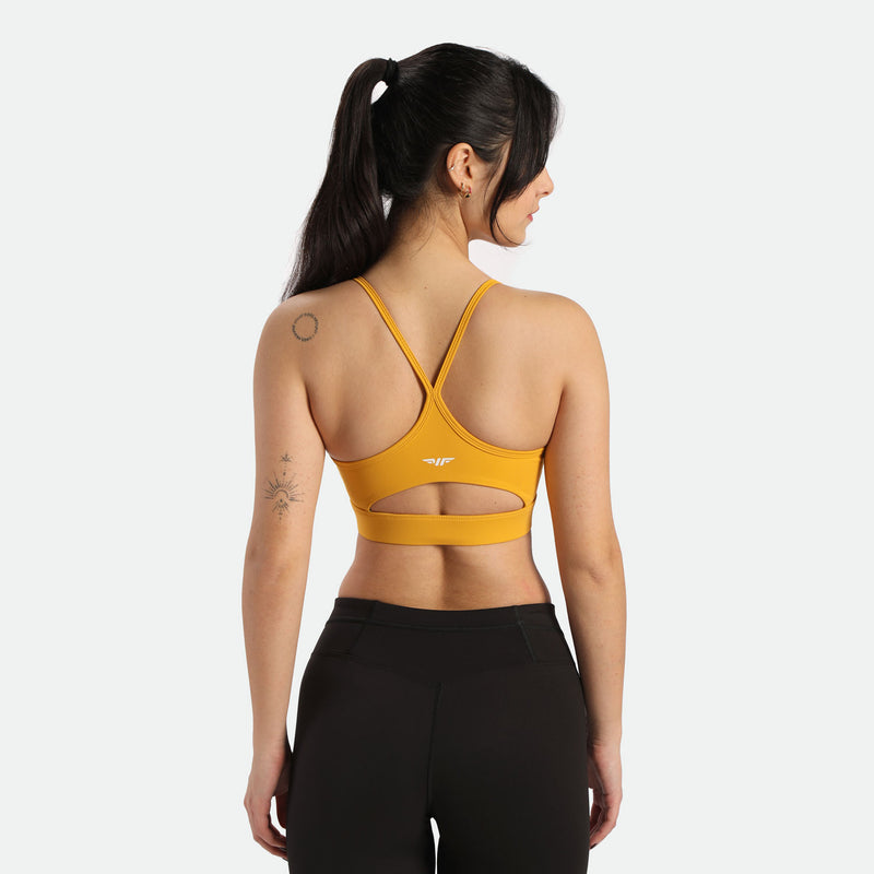 Woman wearing yellow sports bra and legging black , standing with her back to the camera